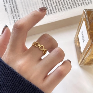 Close-up of minimalist gold chain ring with bead texture on finger with elegant props