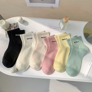 Five pairs of SMILE embroidered cotton socks in Morandi colors displayed on a white table