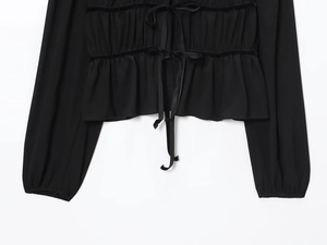 Detail der schwarzen Chiffonbluse mit Vorderfalten und eleganten Doppelschleifen