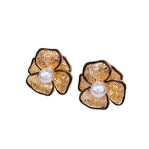 Golden flower earrings with woven petals, black enamel edges, and centered white pearl