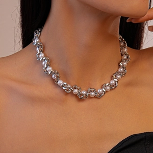 Detail of chunky silver chain intertwined with white pearls on woman's neckline
