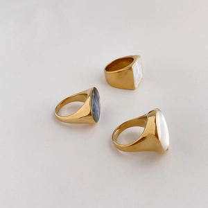 Detailed view of three gold rings featuring inlaid natural mother of pearl and abalone shell