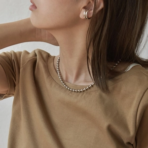 Detailed view of model wearing minimalist silver bead necklace and double-layer ear cuff