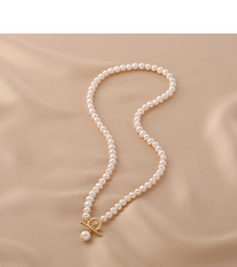 Detail showing natural freshwater pearls with a gold OT toggle clasp on beige silk