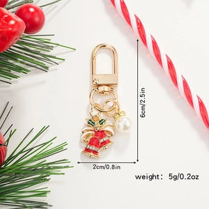 Close-up of golden Christmas keychain with red enamel bell and pearl showing dimensions 6x2cm