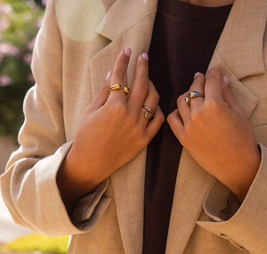 Close-up of a model wearing minimalist silver and gold waterdrop open rings on fingers