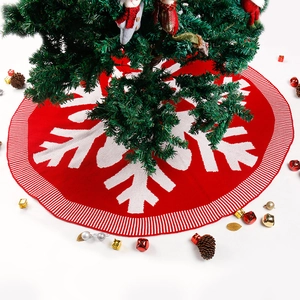 Red and white knitted Christmas tree skirt with large snowflake pattern and striped border