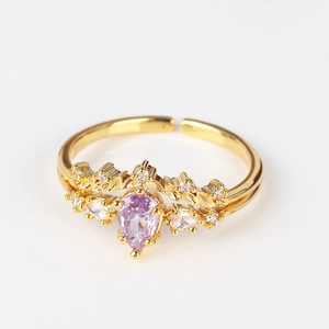 Macro detail of 18K gold ring with purple pear-shaped zircon and leaf crown design