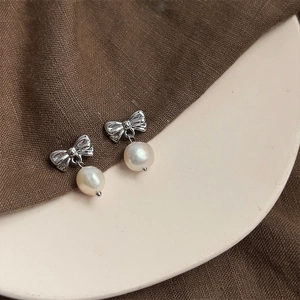 Detailed shot of vintage silver bow earrings with round white baroque pearls