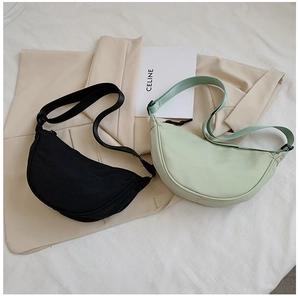 Detail of minimalist nylon crescent bags in black and mint green with adjustable straps