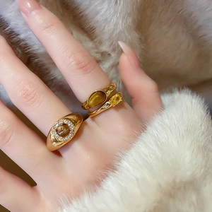 Detailed close-up of gold-plated rings featuring a tiger eye stone and zircon accents