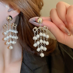Elegant silver open hoop earrings with dangling white pearl tassels on a fashion model