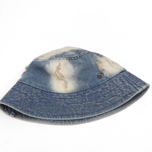 Detail of washed denim bucket hat with distressed holes and a small metal logo badge