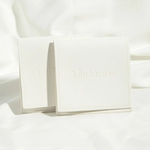 Close-up of two beige PU leather drawstring pouches with embossed text on fabric background