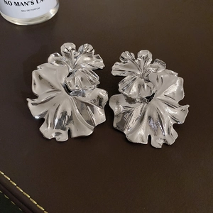 Macro shot of silver oversized floral earrings with pleated metallic petal texture