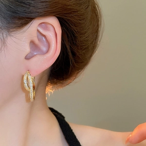 Detail of 18k gold plated U-shape earrings with zircon crystals on model ear
