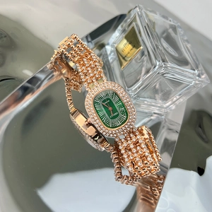 Detail of luxury rose gold oval watch with green dial and rhinestones on mirrored surface
