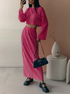 Detail of hot pink pleated two-piece set featuring long sleeves and a high waist maxi skirt