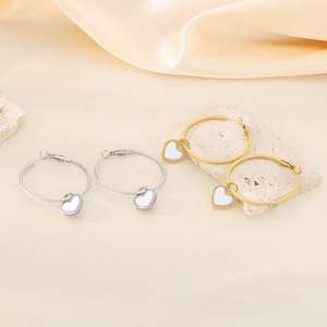Elegant gold and silver heart drop earrings displayed on silk and stone base