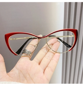 Close-up of red and gold cat-eye glasses frame held in hand with premium metal details