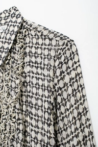 Close-up of geometric print chiffon shirt with gold stripes and ruffled collar detail