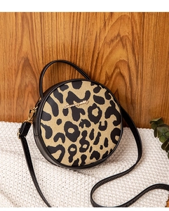 Close-up of leopard print round crossbody bag with leather trim and gold metal details