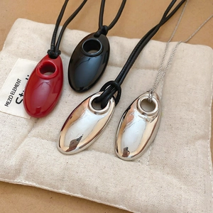Detail of minimalist oval pendant necklaces with leather cord on natural linen bag
