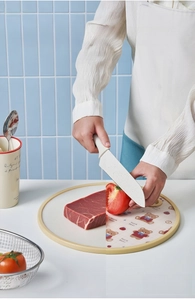 Detailed view of a double-sided PE cutting board with meat and tomato in a kitchen setting