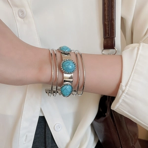 Close-up of layered silver-tone open cuff bracelet with blue turquoise stone details