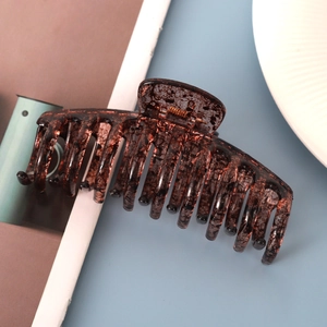 Detail of large tortoiseshell hair claw clip with ink splash pattern on blue surface
