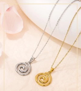 Macro shot of gold and silver swirl necklaces on textured beige paper background