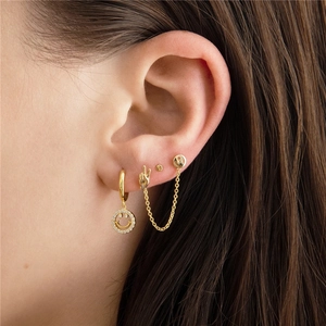 Close-up of gold S925 silver smiley face earrings and studs set worn on model ear