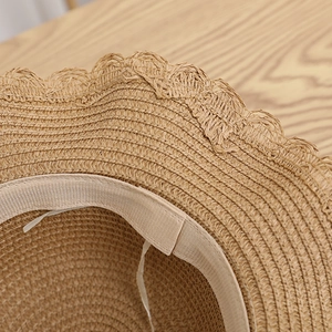 Close-up detail of the woven straw texture and delicate wavy lace trim on the summer sun hat