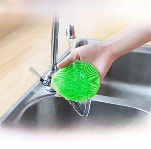 Macro view of green silicone dish brush with soft bristles being rinsed under water
