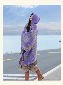 Ethnic style purple hooded poncho with geometric patterns and tassels shown in nature
