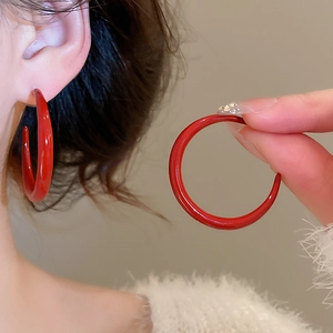 Close-up of vibrant red C-shaped hoop earring showing glossy finish and size reference