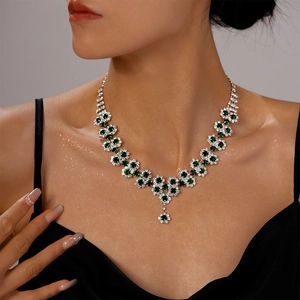 Detailed view of luxury silver floral necklace with green zircons on a model