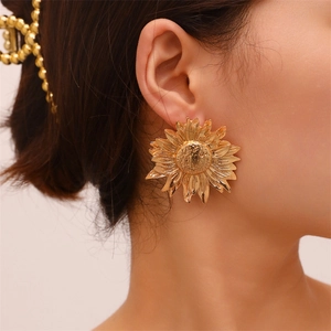 Detailed view of irregular sunflower leaf earrings in golden metal on model