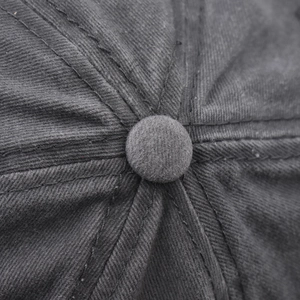 Macro detail of top button and reinforced stitching on a washed cotton baseball cap