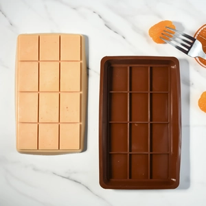 Molde de silicona para chocolate de 12 cavidades sobre mármol blanco con rodajas de naranja