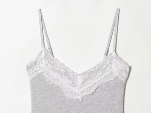 Detailansicht der weißen Blumenspitze und des grauen Strickstoffs am V-Ausschnitt Top