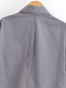 Detail view of the back seam and turned-down collar on a grey cropped shirt for women