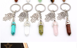 Detail of five Hamsa hand keychains with various colorful hexagonal crystal pendants
