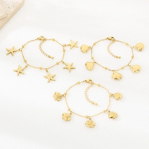 Macro shot of gold stainless steel shell and starfish charms on a beach style bracelet