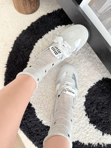Close-up of stylish grey polka dot socks worn with designer leather sneakers on a rug