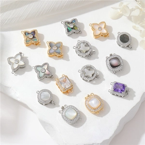 Golden and silver clover jewelry clasps with zircons and mother of pearl on white rocks