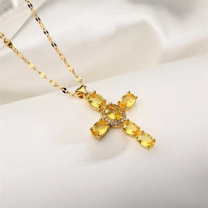 Detailed close-up of gold cross pendant with yellow zircon stones and diamond accents