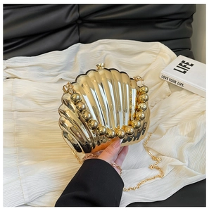 Detailed view of golden shell evening bag with pearl bead handle and metallic finish