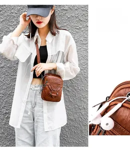 Detail of brown PU leather crossbody bag with three zipper pockets and woven texture