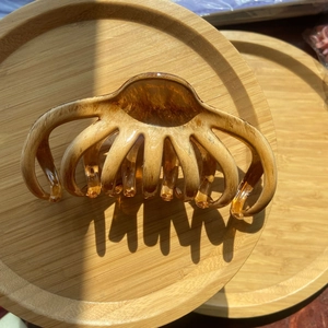 Detail of amber translucent large claw clip with 9 teeth on a wooden tray